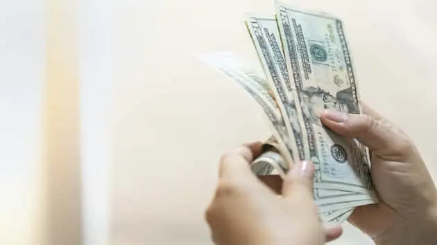 money-business-shopping-and-saving-concept-close-up-of-woman-hand-holding-and-counting-us-dollar-banknote-with-copy-space