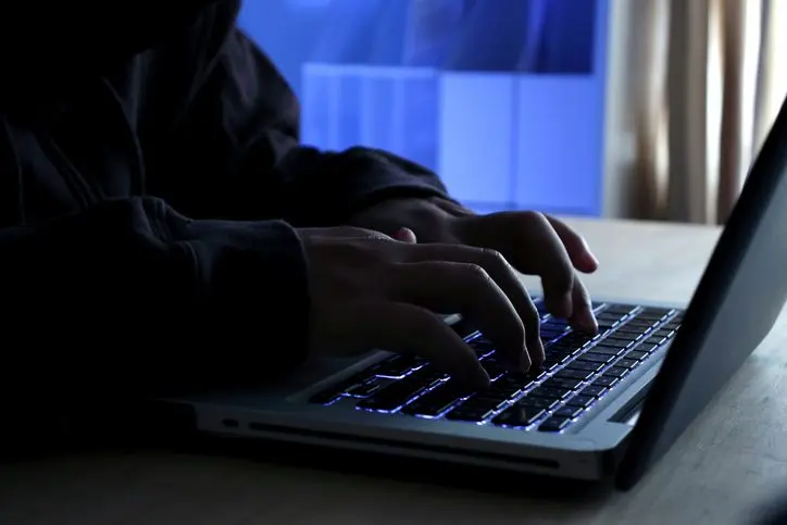 hacker-working-on-laptop-at-night-under-blue-light