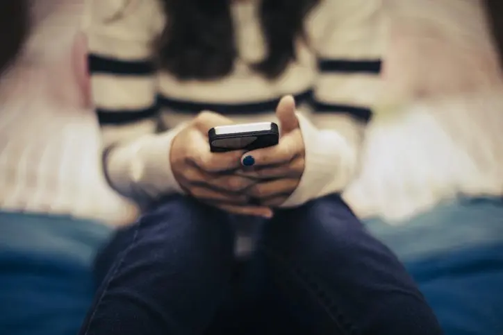 close-up-of-teenage-girl-in-bedroom-using-smart-phone