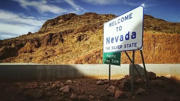 welcome-sign-on-field-against-rocky-mountains