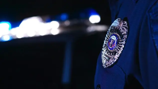 close-up-of-an-officers-badge-with-the-police-lights-on-the-car-flashing-in-the-background