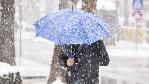 man-with-umbrella-under-snow-on-city-street