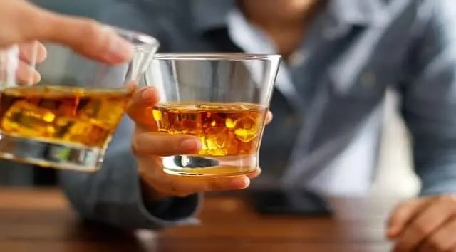 close-up-two-men-clinking-glasses-of-whiskey-drink-alcohol-beverage-together-at-counter-in-the-pub