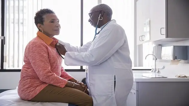 smiling-female-doctor-examining-senior-patient-in-hospital