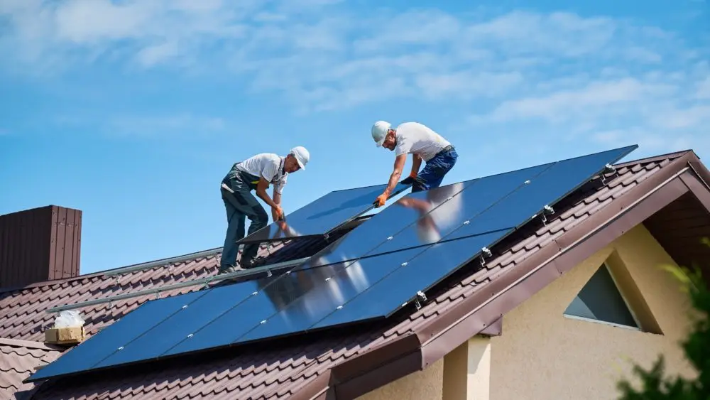 workersbuildingsolarpanelsystemonrooftopofhouse-two