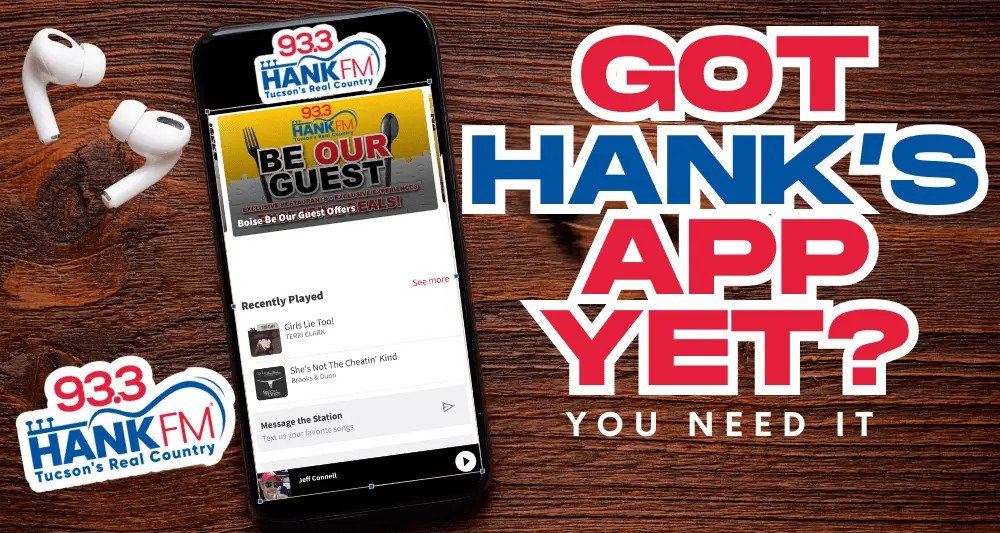 Promotional image for 93.3 HANK FM Tucson’s Real Country app. The ad features a smartphone displaying the HANK FM mobile app with a “Be Our Guest” restaurant promotion on screen. White wireless earbuds rest on a wooden surface beside the phone. Large red and blue text on the right reads “GOT HANK’S APP YET? YOU NEED IT.” The 93.3 HANK FM logo appears twice — on the phone screen and in the bottom left corner.