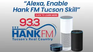 Promotional image for 93.3 Hank FM Tucson featuring Amazon Alexa devices and the text: “Alexa, Enable Hank FM Tucson Skill.” A red button in the center says “CLICK TO LEARN MORE.” The station's logo and slogan “Tucson’s Real Country” are displayed below. Three Amazon Echo devices (Echo Dot, Echo, and Echo Plus) are shown on the right side.