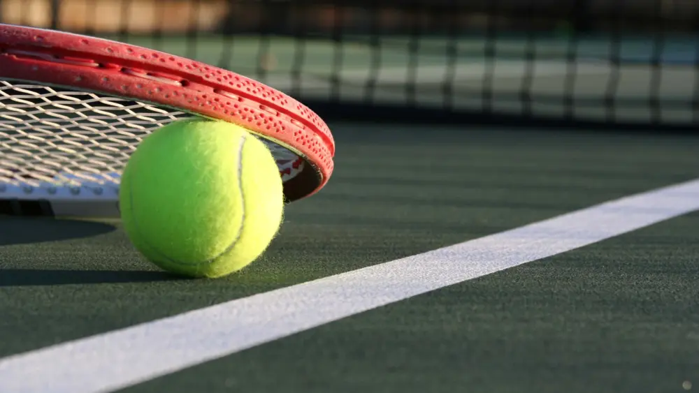 tennis-ball-racket-on-a-green-outdoor-court