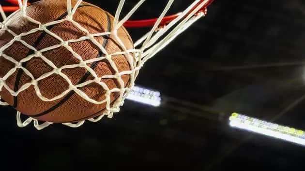 looking-up-at-the-bottom-of-a-basketball-falling-through-the-net-with-arena-lights-in-the-background