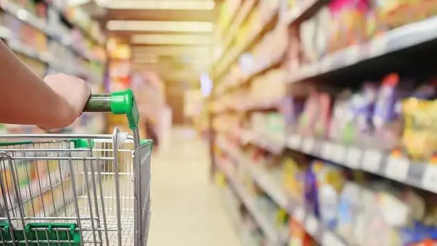 shopping-cart-in-supermarket-aisle-with-product-shelves-interior-defocused-blur-background