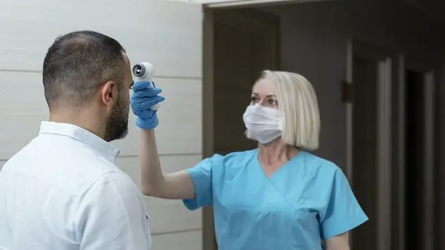 female-doctor-checking-temperature-at-patient-with-infrared-tool-in-hospital