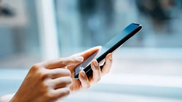 close-up-of-young-woman-using-smartphone-at-home-in-sunlight