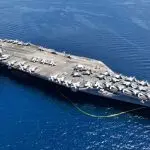 Aerial drone photo of USS Gerald R. Ford latest technology nuclear powered aircraft carrier anchored in deep blue open ocean sea
