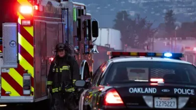 A firefighter stands outside a blaze at a transfer station in East Oakland. Two RVs caught fire in the enclosed lot. Oakland^ California - April 18^ 2026
