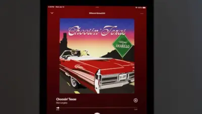 An Apple iPad displays the Spotify music streaming application^ which is playing the song "Choosin' Texas" by the artist Ella Langley