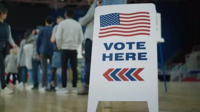 Vote here sign on the floor. Queue of multi ethnic American citizens come to vote in polling station. National Election Day in United States. Political races of US presidential candidates. Civic duty.