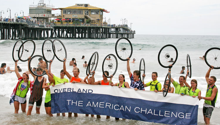 Henry Harris, center wearing the USA shirt in the middle of the picture, celebrates the successful cross-country bicycle adventure by dipping his back tire in the Pacific Ocean.