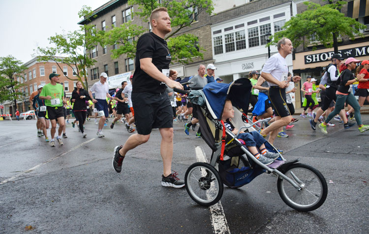 Port Chester resident Chris Budden races, with child in tow, during the Memorial Day Jim Fixx Road Race in Greenwich. (photo courtesy of Michael Yardis / Threads and Treads)