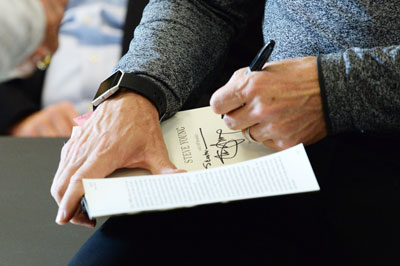Greenwich native and San Francisco 49er legend Steve Young signs a copy of his new book at the Cos Cob Library Monday. (John Ferris Robben photo)