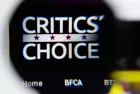 Photo of Critics' Choice Awards homepage on a monitor screen through a magnifying glass.