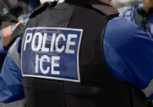 ICE police agent - Officer of Immigration and Customs Enforcement. Close-up of POLICE ICE marking on the back of a stab proof vest uniform worn by a trio of police officers at the scene of an immigrant incident. The ICE federal law enforcement agency is under the supervision of the United States Department of Homeland Security.