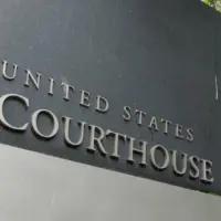 The United States Courthouse sign stands tall amidst a serene backdrop of trees at the US District Court in Seattle^ Washington. Seattle - May 17^ 2019: