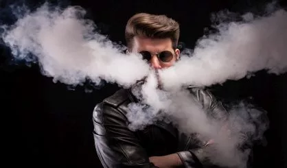 fashionable-bearded-man-with-stylish-glasses-in-leather-jacket-vaping-electronic-smoke