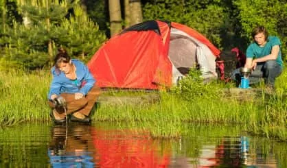 camping-couple-heating-supper-and-washing-pot