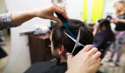 unrecognizable-hairdresser-cutting-hair-of-her-young-client