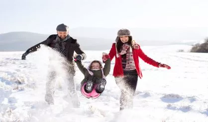 father-and-mother-with-their-daughter-playing-in-the-snow