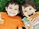 two-cute-boys-laying-on-ground-in-nature-and-happily-eating-healthy-food