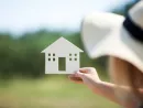 woman-holding-house-model-in-the-countryside