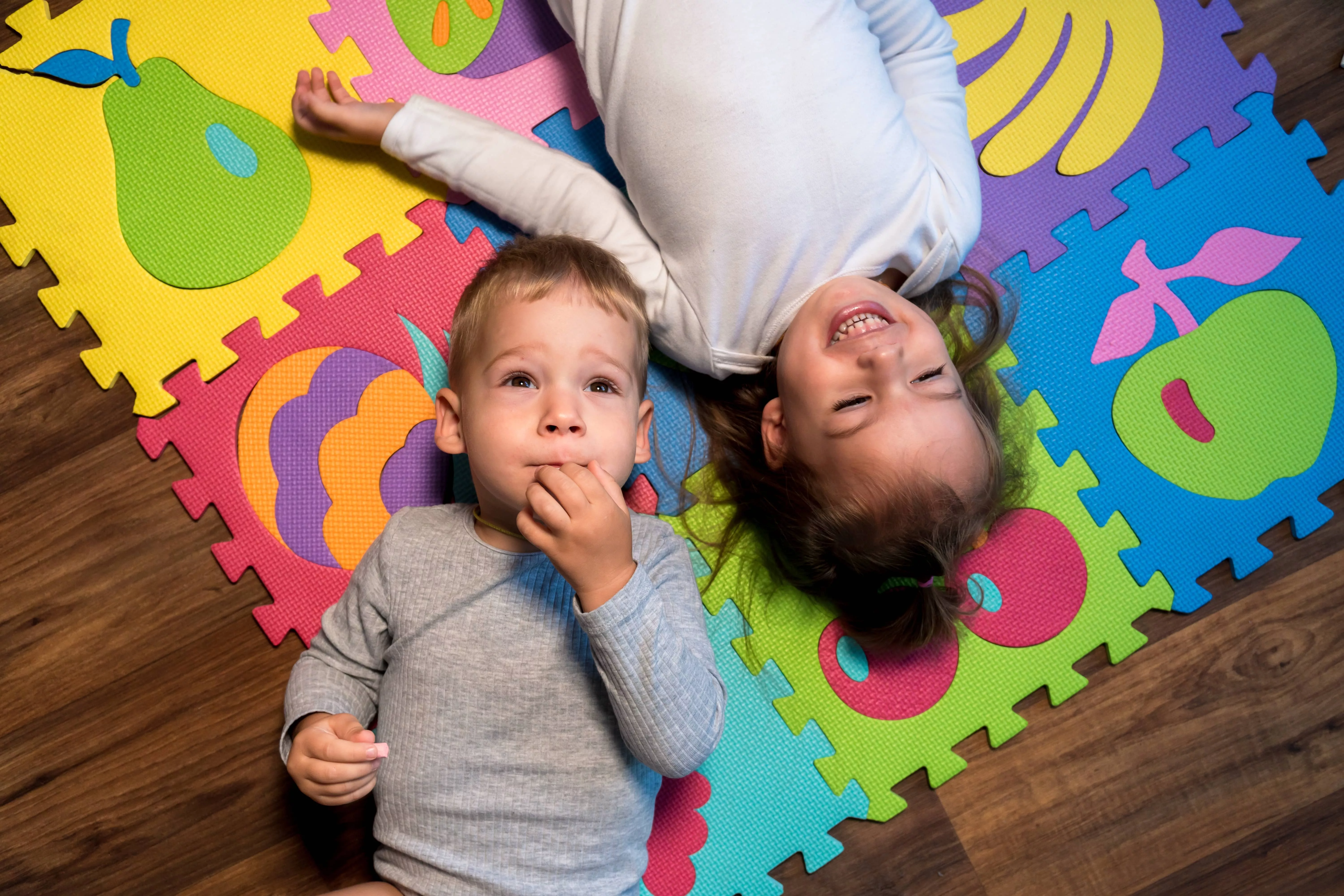 childhood-family-friendship-games-close-up-portrait-two-funny-joy-happy-smiling-little-toddler-peschool-kids-siblings-twins-brother-with-sister-have-fun-lie-playing-on-puzzles-mat-at-home-indoors