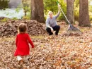 toddler-girl-running-to-her-father-raking-leaves-in-the-fall