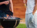 cropped-image-of-two-men-holding-beer-bottles-while-barbecue