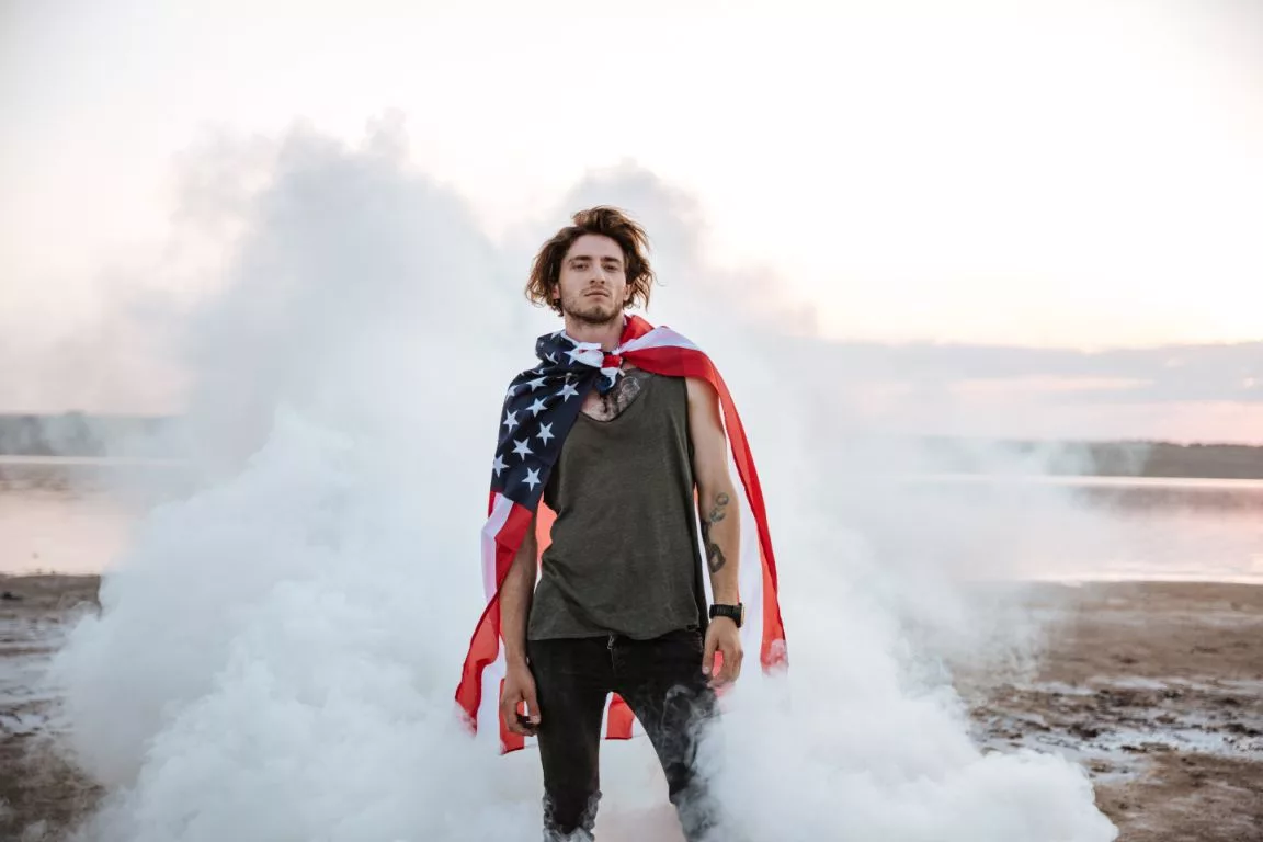 brutal-man-wearing-usa-flag-cape-posing-in-white-smoke