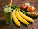 glass-of-green-smoothie-with-yellow-straw-on-a-wooden-table-next