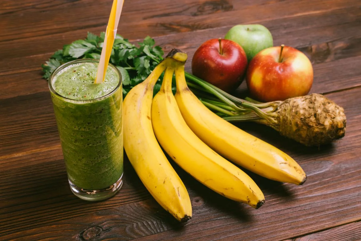 glass-of-green-smoothie-with-yellow-straw-on-a-wooden-table-next