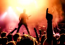 silhouette of guitar player in action on stage in front of concert crowd