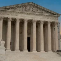Greek classical architecture of the United States Supreme Court building with sunrise in background.