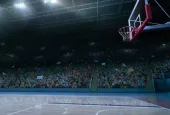 empty basketball court; shot of hoop and crowd in background