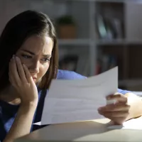 worried-woman-reading-letter-at-night-at-home