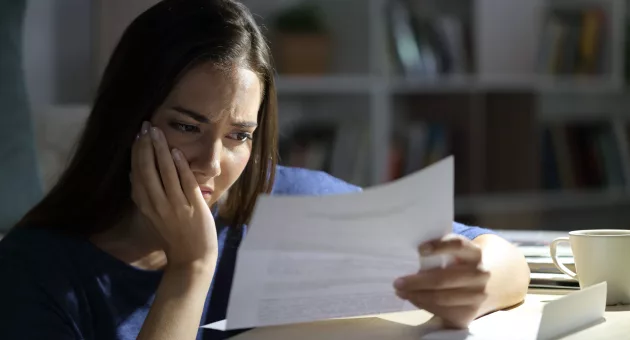 worried-woman-reading-letter-at-night-at-home