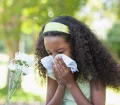 young-girl-sitting-by-flower-and-blowing-her-nose-in-the-park