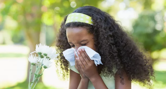 young-girl-sitting-by-flower-and-blowing-her-nose-in-the-park