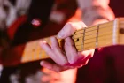 Close up look of hands of a man playing the electric guitar during a concert