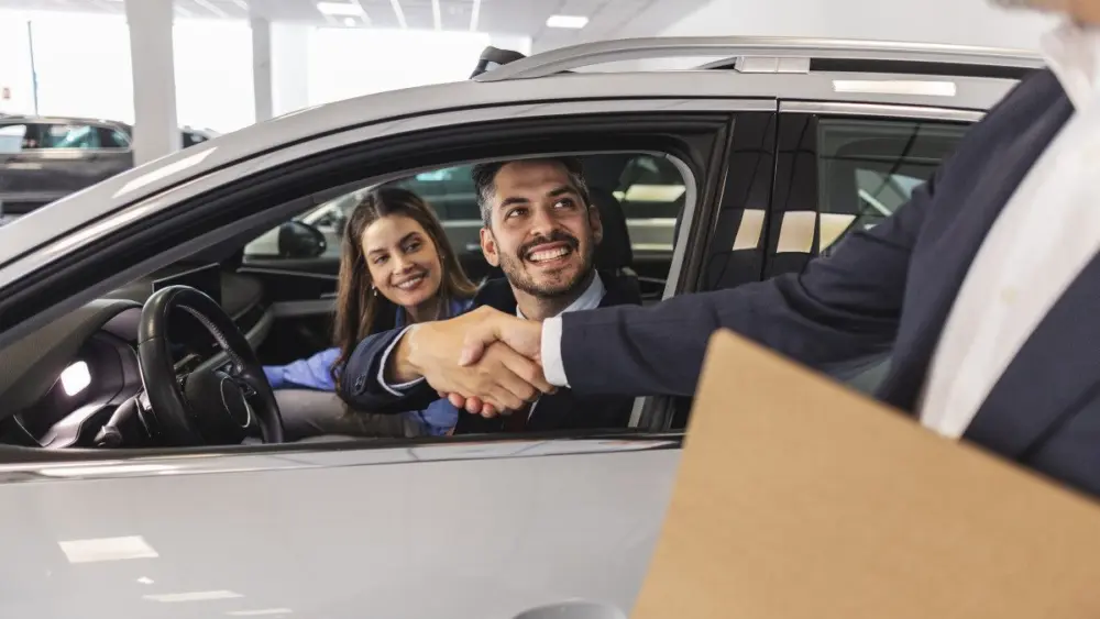 happy-couple-shaking-hands-with-car-salesman-in-dealership820626