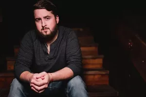 Jake Bush sitting on steps, showcasing his laid-back style