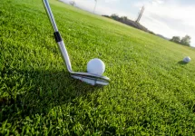 A golf club lined up to hit a ball on the course, symbolizing determination and skill.