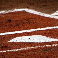 Home plate with red dirt and the batter's box, symbolizing the intensity of high school baseball playoffs.